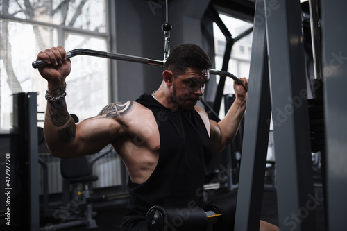 Muscular strong bodybuilder exercising on vertical row lat pulldown gym machine © mad_production
