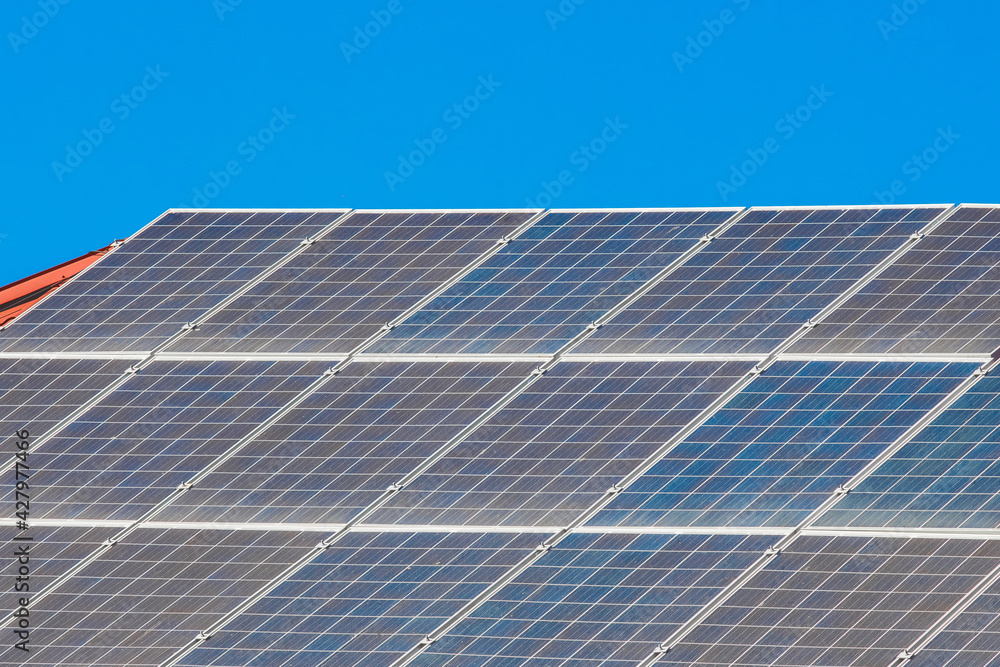 Solar panels on the roof of a building against a blue sunny sky Solar panels on the roof of a building against a blue sunny sky
