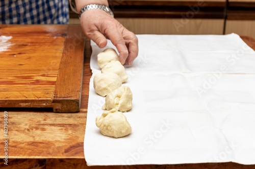 Female hand lays out pieces of yeast dough on white cloth, portioning dough for buns on the table photo