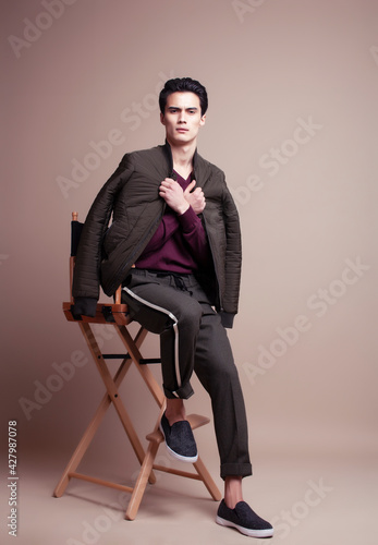 young pretty asian man posing in fashion style on light brown background, lifestyle people concept