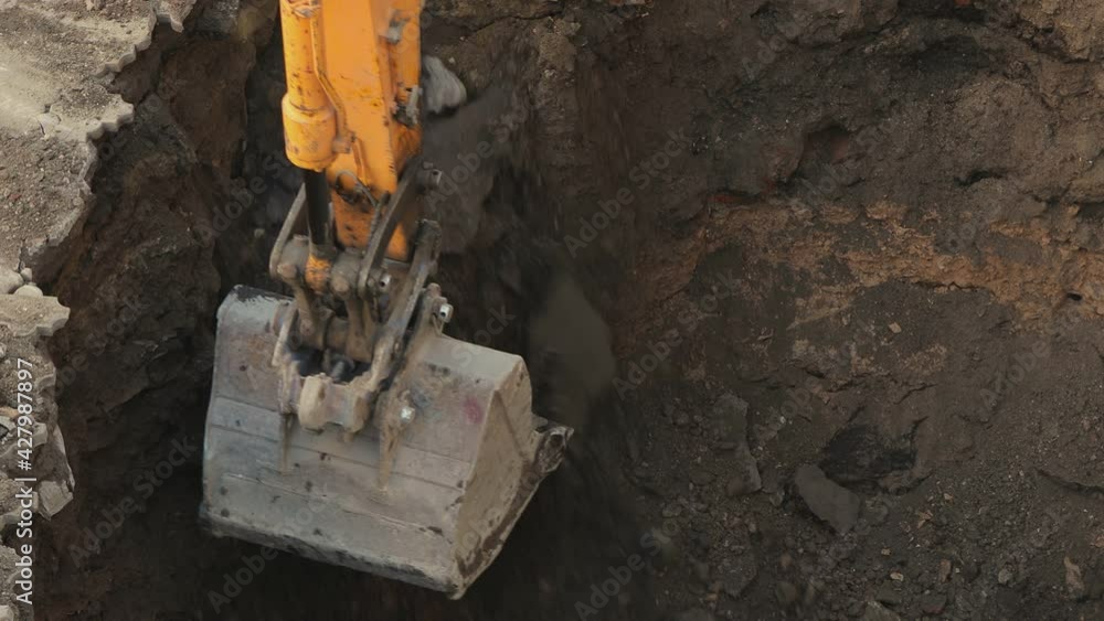 Big metal excavator bucket scoops up ground . Ripper bucket excavating soil and rocks at a construction site . Close up bulldozer digging building foundation in slow motion. Tractor working Big metal excavator bucket scoops up ground . Ripper bucket excavating soil and rocks at a construction site . Close up bulldozer digging building foundation in slow motion. Tractor working