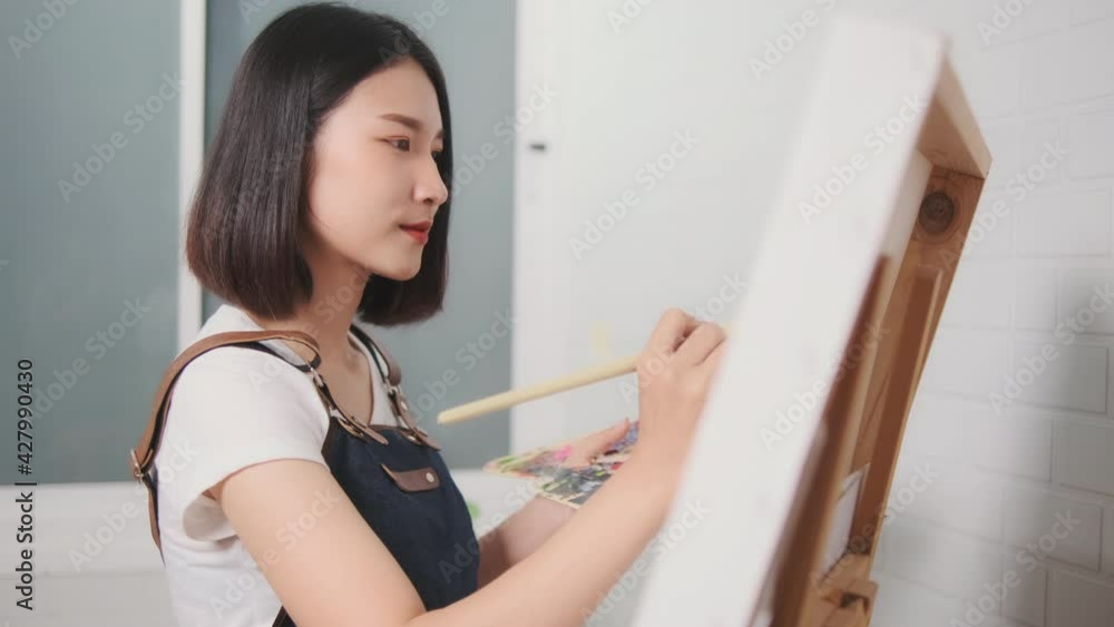 Asian woman artist painting picture with blank canvas side view, using paint brush and colour pallets having fun creativity activity occupation hobby concept, creative thinking imagination visual Asian woman artist painting picture with blank canvas side view, using paint brush and colour pallets having fun creativity activity occupation hobby concept, creative thinking imagination visual