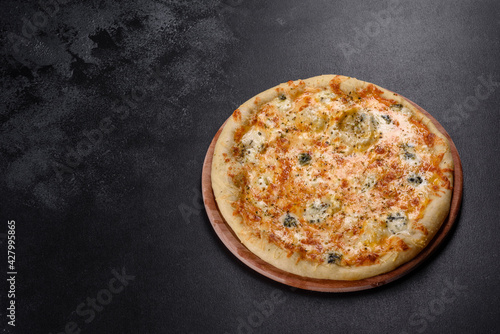Tasty fresh oven pizza with tomatoes, cheese and mushrooms on a dark concrete background