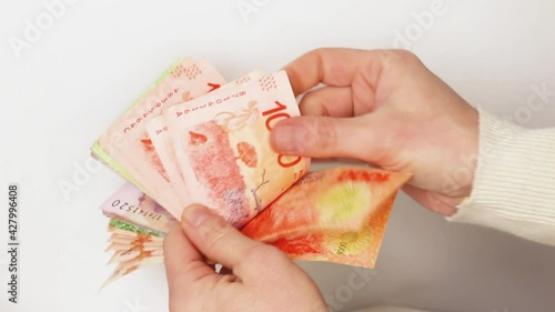 Woman Hands with natural and unpolish short nails counting argentine money in a close up fom a high view,  with a isolated white background in a indoor neutral space