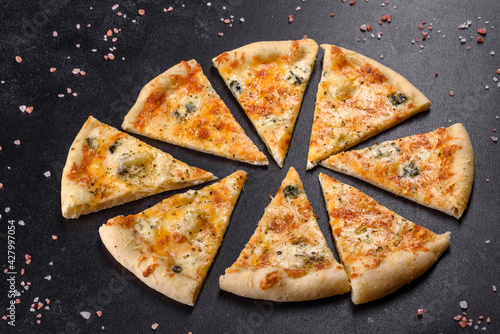 Tasty fresh oven pizza with tomatoes, cheese and mushrooms on a dark concrete background