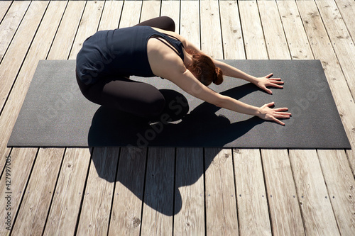 Slim young woman meditating, relaxing and practicing yoga on the wooden pier near lake. photo