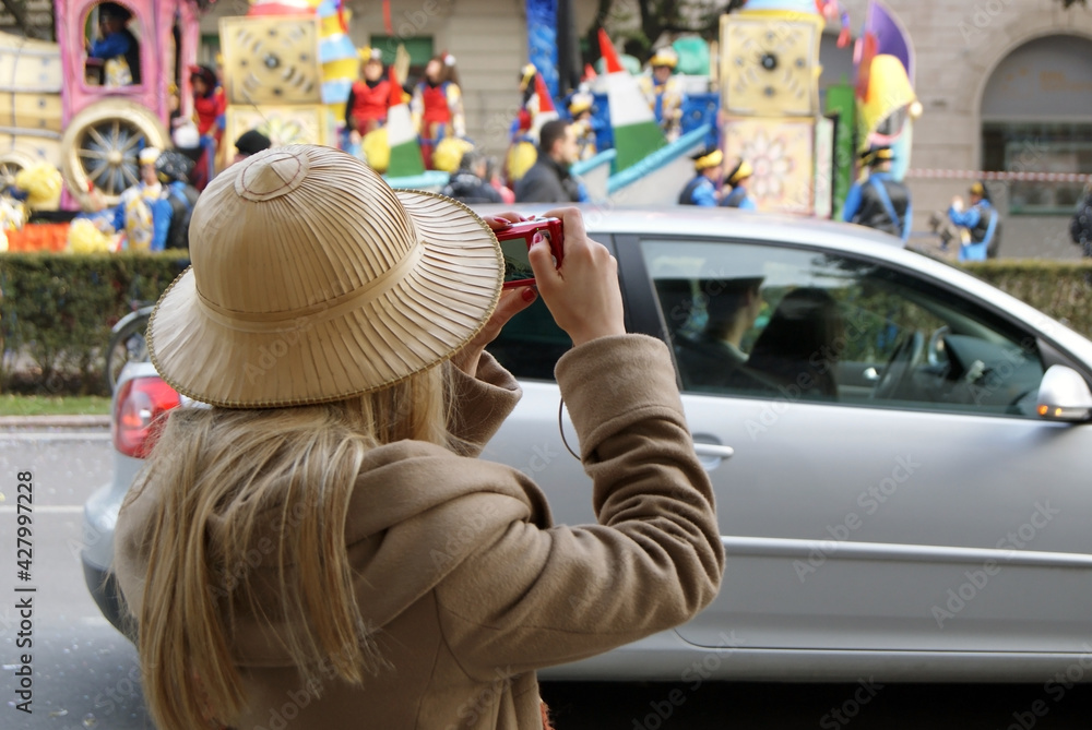 Blonde tourist wearing a colonial hat during the carnival.
Girl photographs the carnival floats in Verona during a parade.