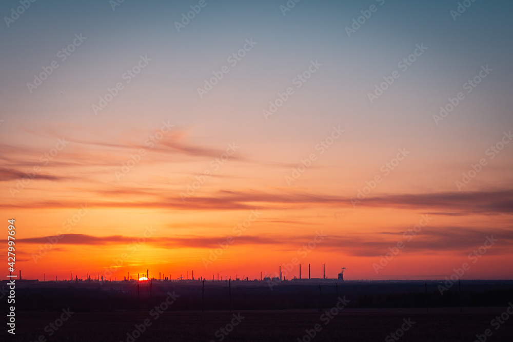 Obraz premium Sunset over an industrial oil refinery (enterprise).