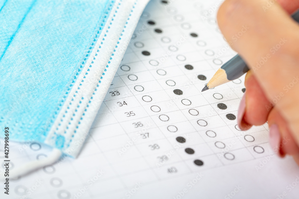testing in exercise and examination work. blue medical mask, sheet with pencil in school test room, education concept during pandemic testing in exercise and examination work. blue medical mask, sheet with pencil in school test room, education concept during pandemic