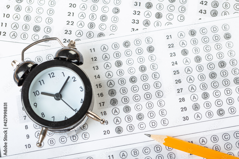 alarm clock, optical form of standardized school test with bubble and black pencil, answer sheet, education concept alarm clock, optical form of standardized school test with bubble and black pencil, answer sheet, education concept