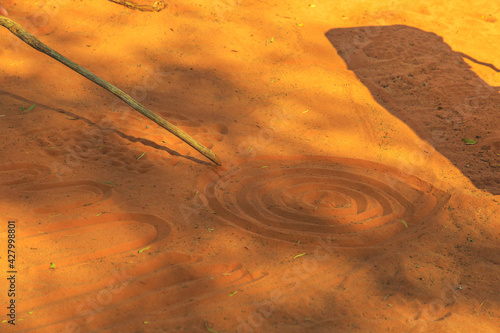 Schilderij op canvas aboriginal people creating shapes with red sand on the ground in aboriginal art style