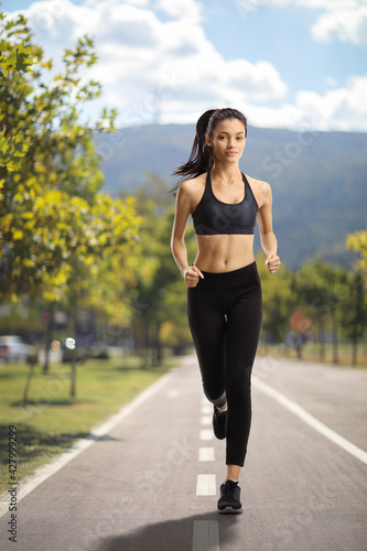 Girl jogging towards camera on a running track