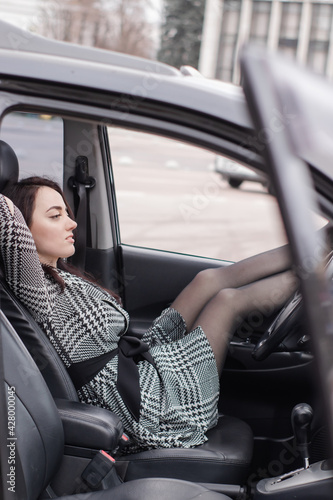 fabulous Female wearing checkered dress in an automobile with legs in red high-heeled shoes sticking out car window © OliaVesna