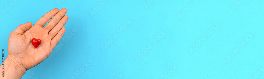 Man gives a red heart in a hand, helping hand and charity concept banner background, copy space Man gives a red heart in a hand, helping hand and charity concept banner background, copy space