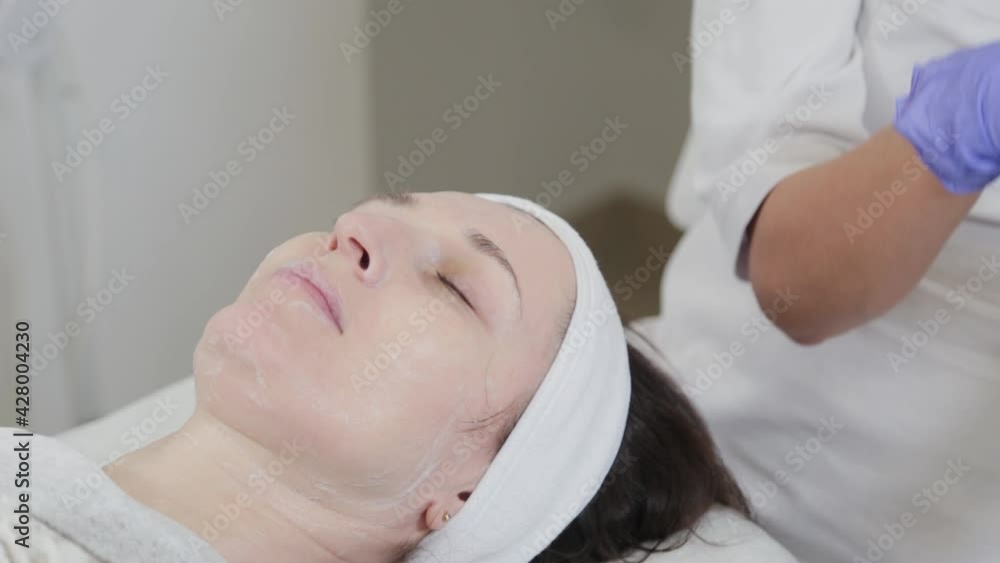 Professional beautician woman washes face to client with napkins. Professional beautician woman washes face to client with napkins.