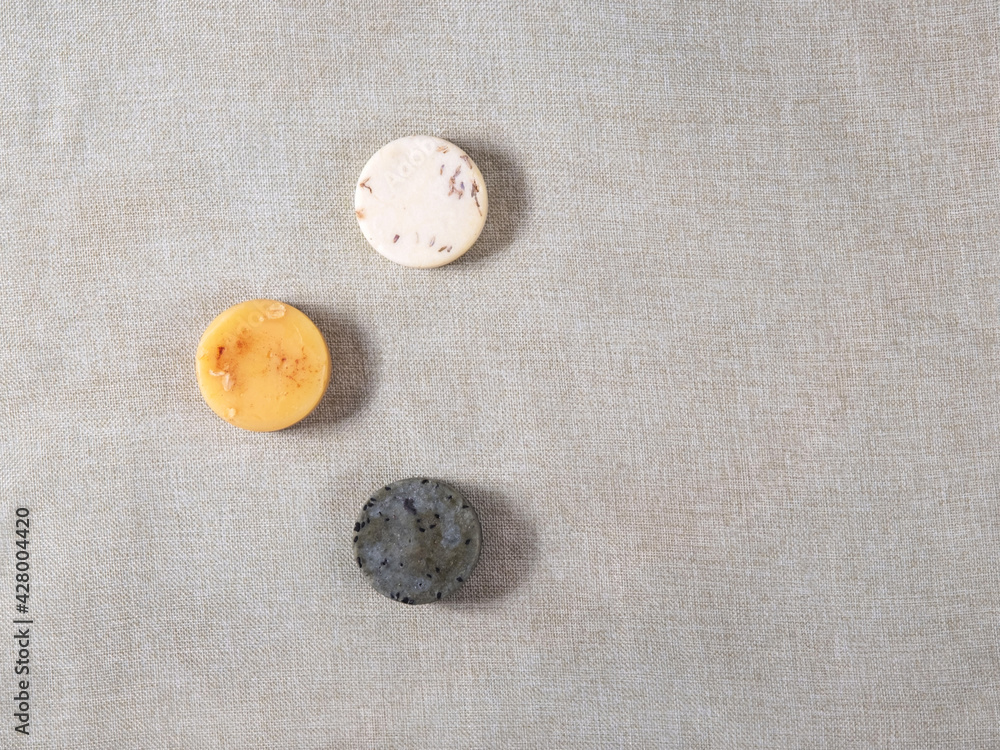 Three round natural handmade soaps on the cotton background with the copy space for your text. Zero waste concept of bathing without any package and only with natural ingredients. Three round natural handmade soaps on the cotton background with the copy space for your text. Zero waste concept of bathing without any package and only with natural ingredients.