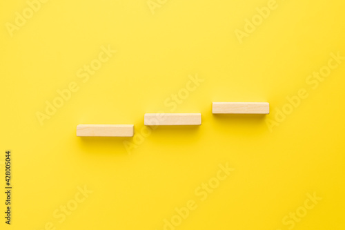 stairs made by wooden bricks over yellow background. above view. abstract creative staircase. business strategy concept. achievement conceptual photo
