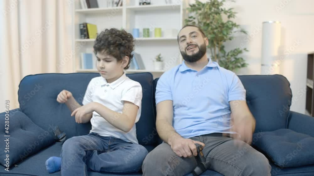 Dad and son playing video game together, upset with loss, family leisure Dad and son playing video game together, upset with loss, family leisure
