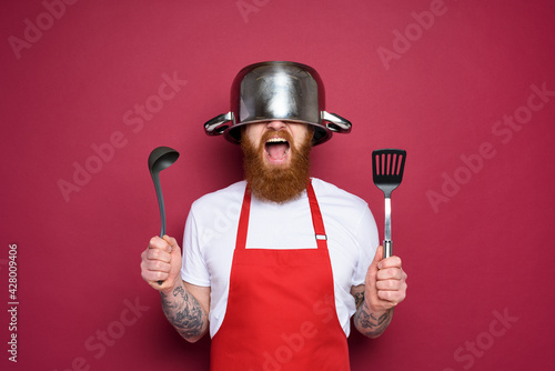 Obraz na plátně Man chef is ready to fight in the kitchen. burgundies background