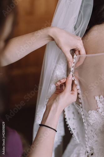 gathering of the bride, buttoning up a wedding dress close-up, buttons and woman's hands, an unbuttoned dress