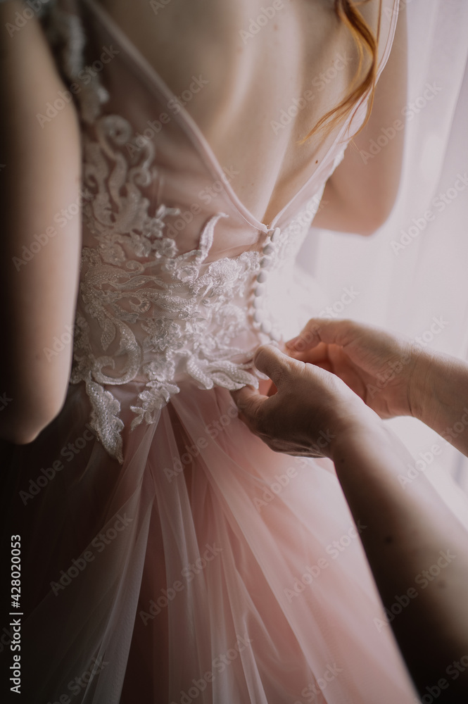 gathering of the bride, buttoning up a wedding dress close-up, buttons and woman's hands, an unbuttoned dress gathering of the bride, buttoning up a wedding dress close-up, buttons and woman's hands, an unbuttoned dress