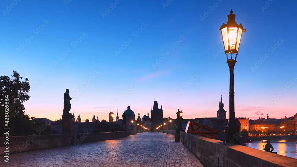 Prague at night, lights on Charles Bridge at dawn, blue pink dawn