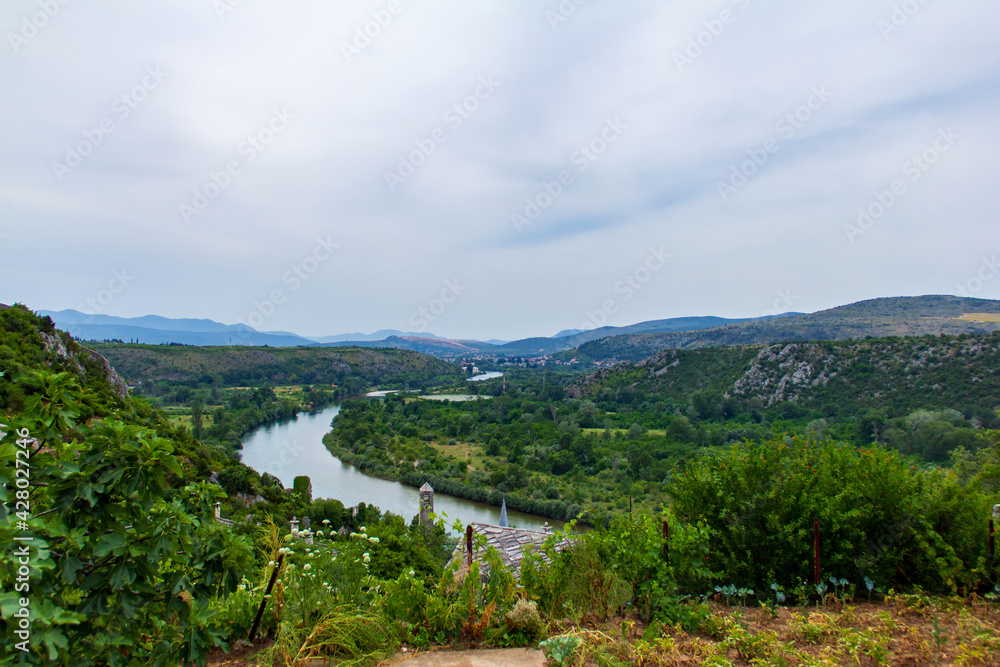 View of old village in Poictelj. Bosnia-Herzegovina during summer sunny cloudy day with mountains and river in the back.
