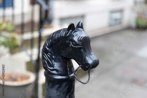 Philadelphia, PA - March 26 2021: Metal black horse head hitching post. Historical piece in front of a blurry home in Philadelphia