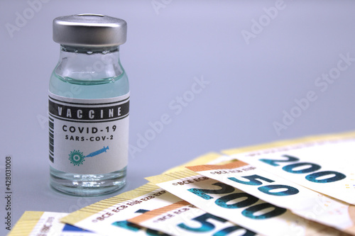 Vaccine vial next to euro banknotes