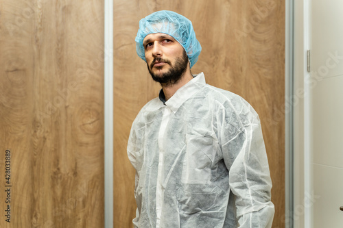 Portrait of caucasian man wearing protective mask and bouffant mob cap - Young male doctor or scientist getting ready for work in the laboratory hospital front view looking to the camera copy space photo