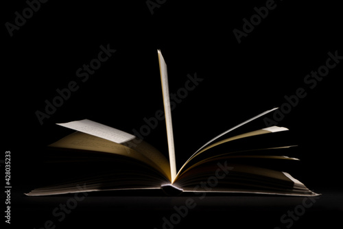 close up of open book pages on black background