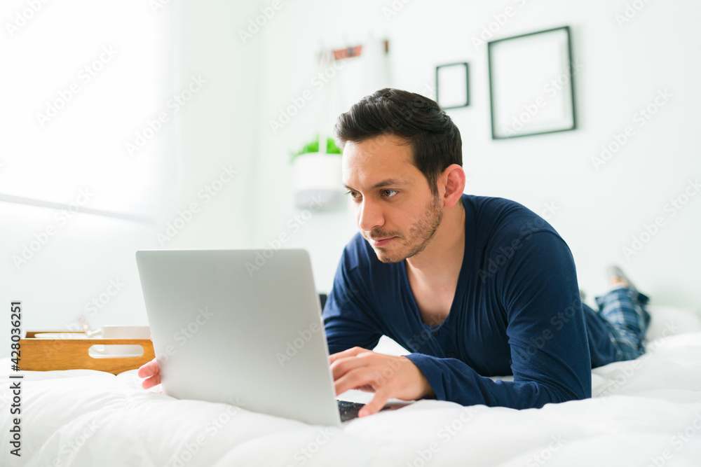Hispanic man in pajamas online shopping on a laptop Hispanic man in pajamas online shopping on a laptop