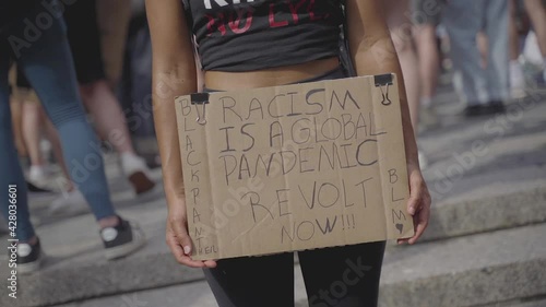 Racism is Global Pandemic Sign in Hands of a Young Female on Black Lives Matter Protest in New York USA, Close Up Slow Motion Detail photo