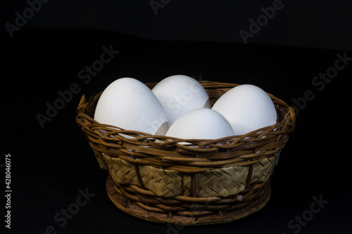 Eggs. Fresh chicken eggs in a wicker basket with black background close up vertical photo with space for text