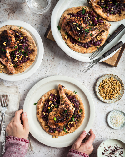 Flatlay of whole roasted chicken legs on a bed of sumac spiced onions and flatbread