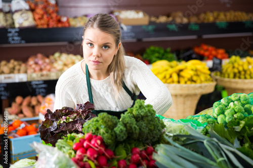 Portrait of young female in apron selling greens and letuce on the market © JackF