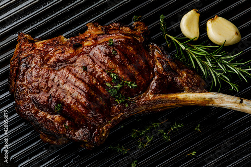 Barbecue grilled Tomahawk Steak on Cast iron Grill surface background close-up