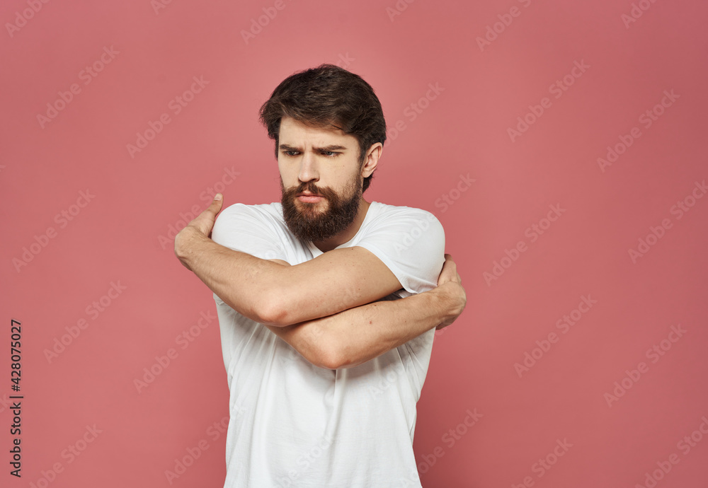 Sad man crossed his arms over his chest on a pink background Sad man crossed his arms over his chest on a pink background