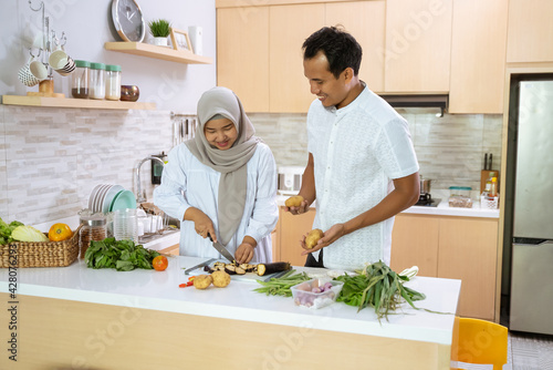husband help his wife in the kitchen. muslim asian couple preparing dinner together. romantic young man and woman have fun making food at home