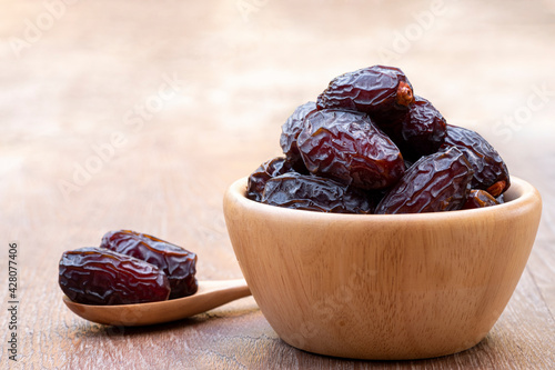 Fototapeta Naklejka Na Ścianę i Meble -  The large date fruits (Medjool) in cups and wooden spoons on a cement with blurred background.