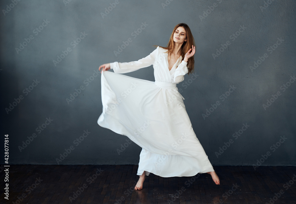 Charming lady in a white dress on a gray background dance gesticulating with her hands model Charming lady in a white dress on a gray background dance gesticulating with her hands model