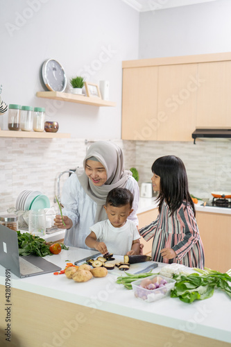 lovely asian woman with daughter and son cooking dinner during ramadan for iftar breaking the fast