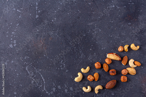 Assortment of various types of nuts on dark background. Cashew, hazelnuts, almonds and Brazil nuts top view. Healthy vegetarian snacks. Protein-containing food. Selective focus.