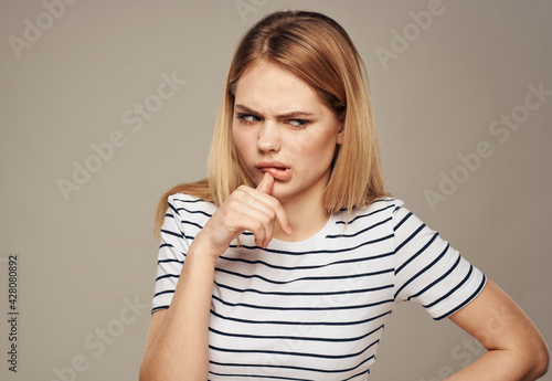Woman disgust beige background striped t-shirt gesturing with hands