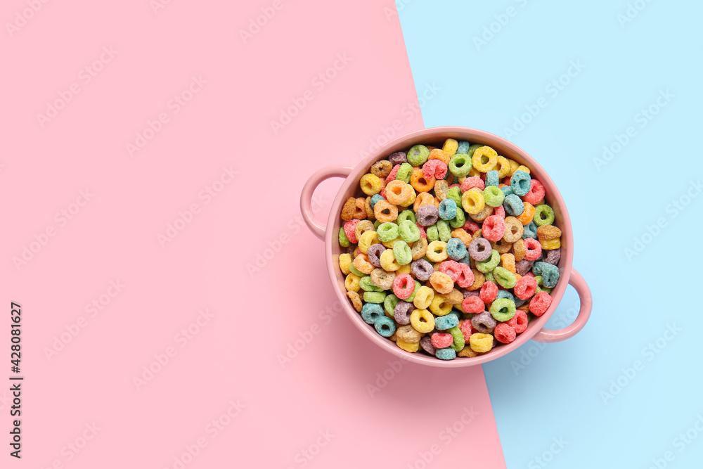 Bowl with crispy cereal rings on color background