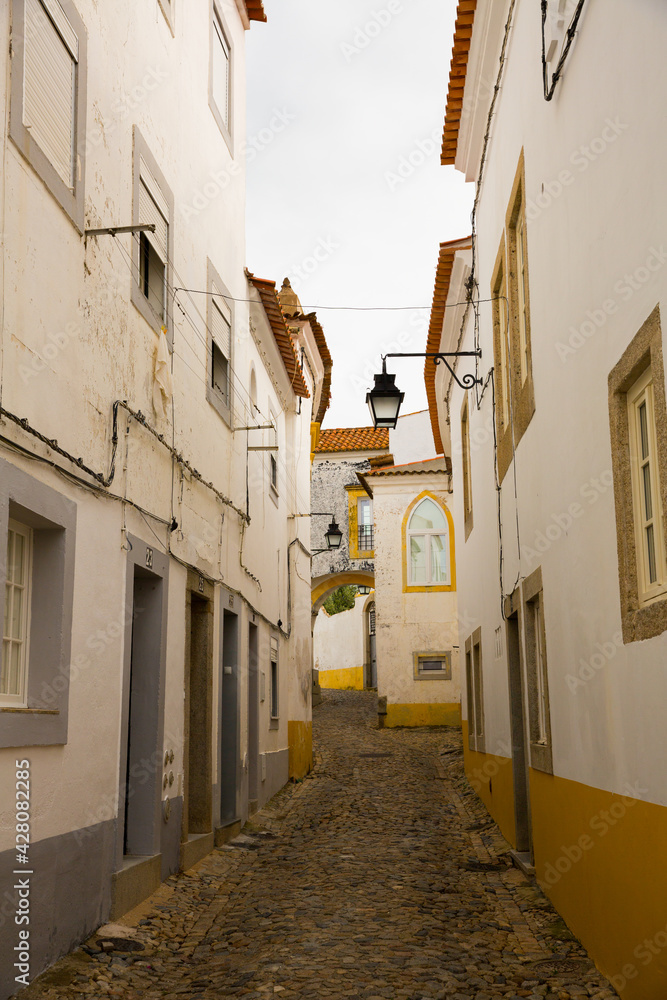 View of narrow street with paving stone and old stone houses of Evora, Portugal