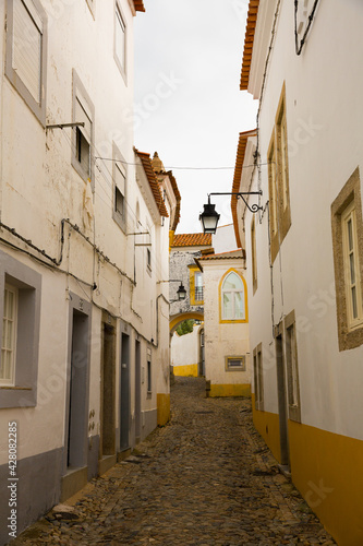 View of narrow street with paving stone and old stone houses of Evora  Portugal