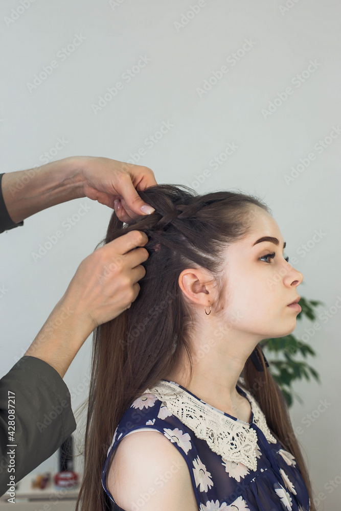 Naklejka premium master makes a hairstyle for a girl, beautiful curls