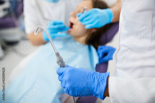 Фотография Close-up of dentist using dental suction tube during appointment with patient at dentist's office