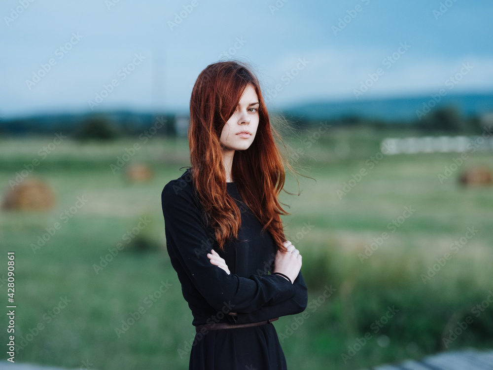 red-haired woman in black dress in nature outdoors